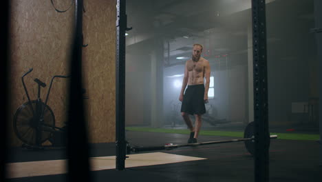 A-male-athlete-lifts-a-weight-bar-with-one-hand-in-slow-motion.-Strength-training-for-a-boxer.-The-man-is-sweating-working-out-in-the-gym-practicing-the-force-of-the-blow-with-his-hand